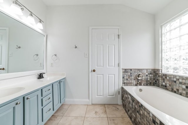 bathroom featuring tile patterned flooring, vanity, lofted ceiling, and tiled tub