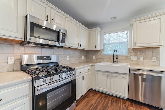 kitchen featuring sink, stainless steel appliances, dark hardwood / wood-style floors, white cabinets, and decorative backsplash