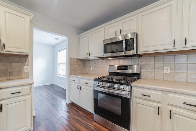 kitchen with tasteful backsplash, dark hardwood / wood-style floors, white cabinets, and appliances with stainless steel finishes