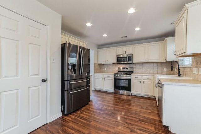 kitchen with appliances with stainless steel finishes, sink, dark hardwood / wood-style floors, and decorative backsplash