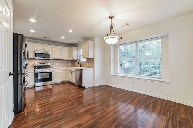 kitchen with white cabinetry, hanging light fixtures, appliances with stainless steel finishes, dark hardwood / wood-style floors, and decorative backsplash