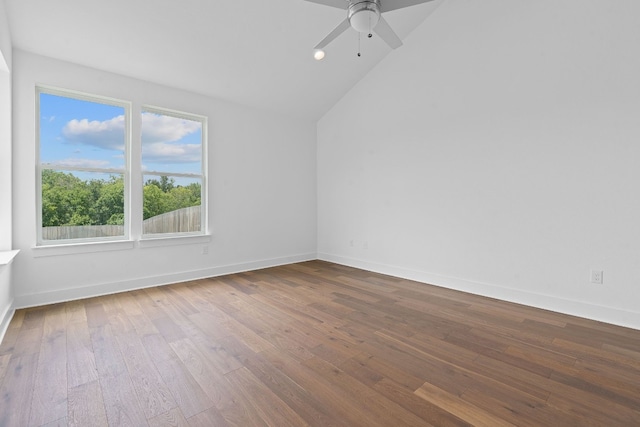 empty room featuring plenty of natural light, ceiling fan, wood-type flooring, and vaulted ceiling