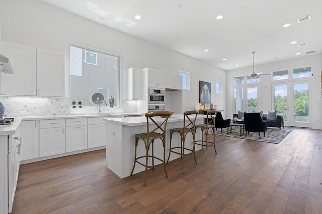 kitchen featuring white cabinetry, dark hardwood / wood-style flooring, a kitchen island, ceiling fan, and decorative backsplash