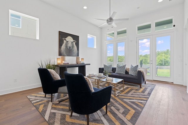 living room featuring ceiling fan, hardwood / wood-style floors, and a towering ceiling