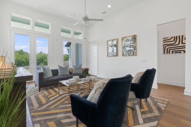 living room with a high ceiling, hardwood / wood-style flooring, french doors, and ceiling fan