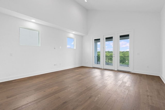 spare room featuring hardwood / wood-style floors and high vaulted ceiling