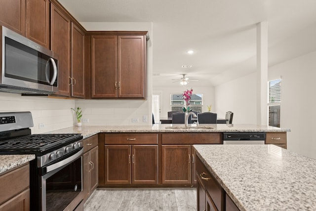 kitchen featuring light hardwood / wood-style flooring, backsplash, ceiling fan, appliances with stainless steel finishes, and sink