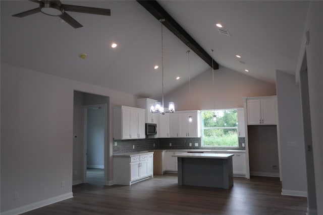 kitchen with beam ceiling, white cabinetry, a center island, and ceiling fan with notable chandelier