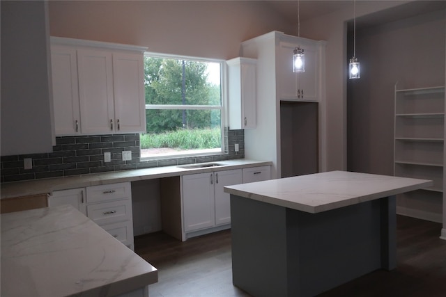 kitchen featuring pendant lighting, a center island, hardwood / wood-style flooring, white cabinets, and backsplash