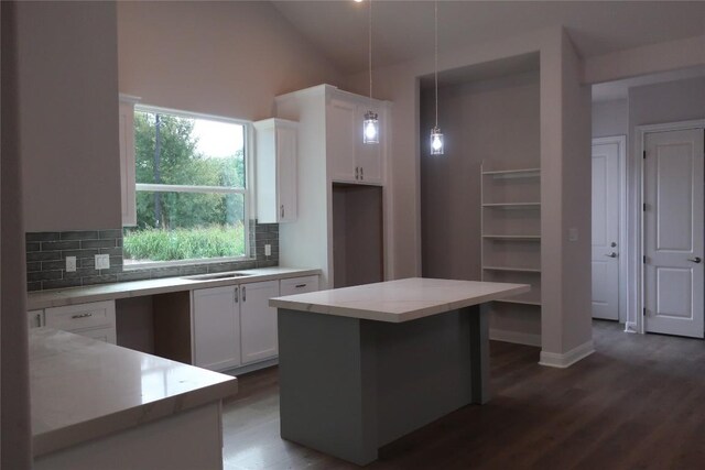 kitchen featuring white cabinetry, a center island, decorative light fixtures, and backsplash