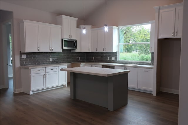 kitchen with white cabinetry, hanging light fixtures, a kitchen island, and dark hardwood / wood-style flooring