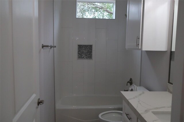 full bathroom featuring tiled shower / bath, vanity, and toilet