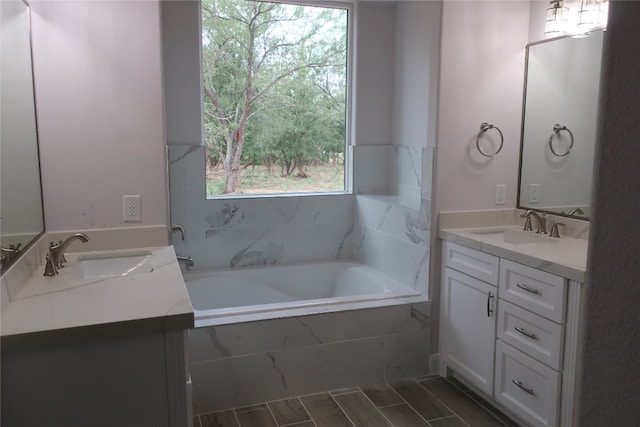 bathroom featuring a relaxing tiled tub and vanity