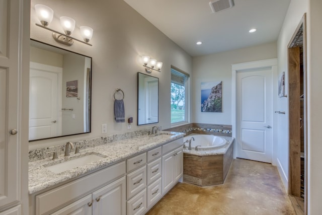 bathroom featuring concrete floors, tiled bath, and double sink vanity