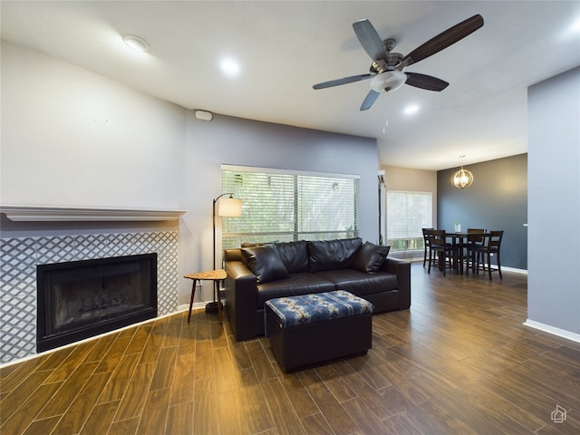 living room featuring a tile fireplace, dark hardwood / wood-style flooring, and ceiling fan