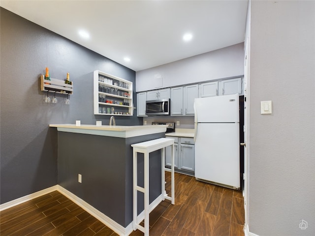 kitchen with sink, white fridge, kitchen peninsula, and dark hardwood / wood-style floors