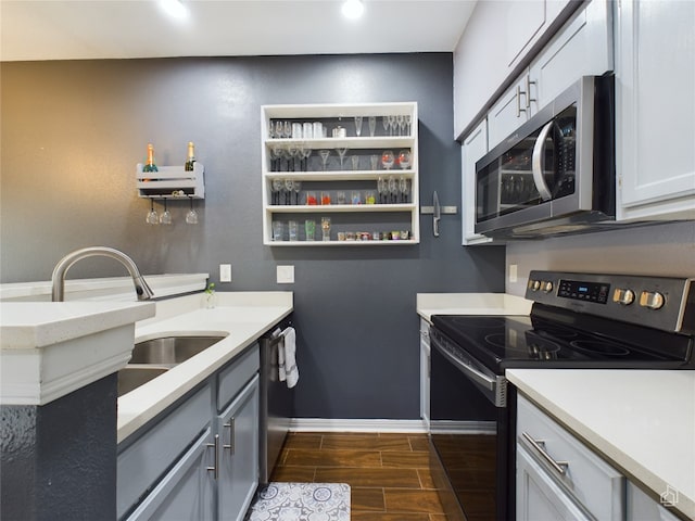 kitchen with sink, dark hardwood / wood-style flooring, stainless steel appliances, and gray cabinetry