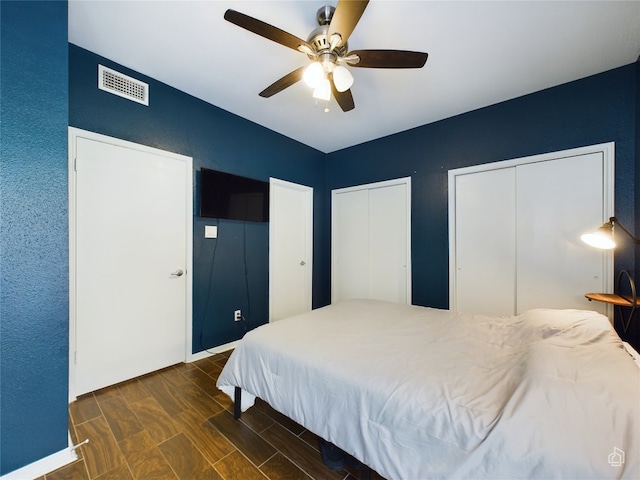 bedroom with two closets, ceiling fan, and hardwood / wood-style floors