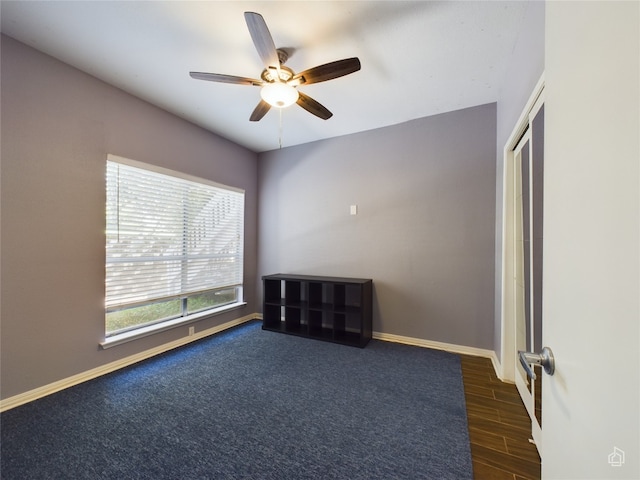 unfurnished room with dark carpet and ceiling fan