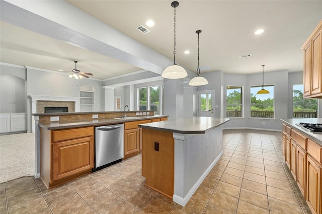 kitchen featuring appliances with stainless steel finishes, sink, light tile patterned floors, a kitchen island, and a tiled fireplace