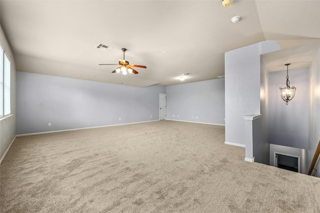 empty room with carpet, ceiling fan with notable chandelier, and vaulted ceiling