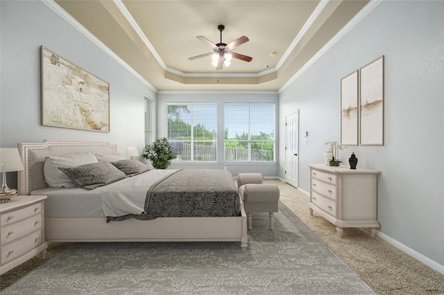 bedroom with ceiling fan, light carpet, ornamental molding, and a tray ceiling