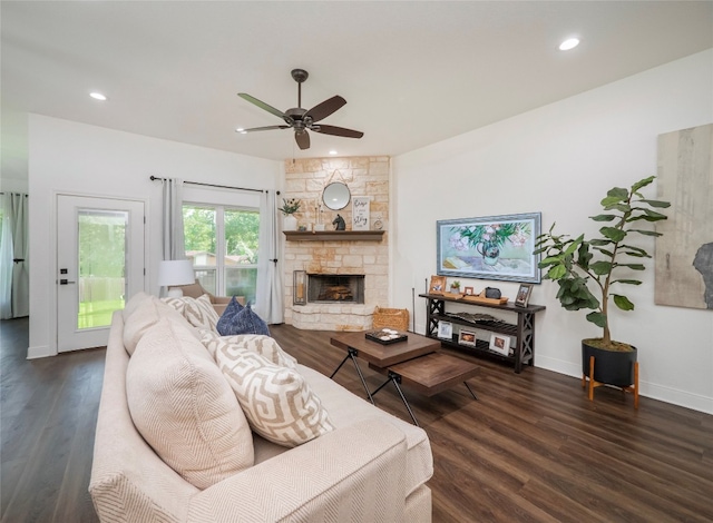 living room with dark hardwood / wood-style flooring, a stone fireplace, and ceiling fan