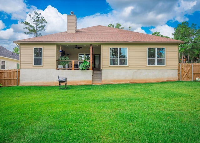 back of house featuring ceiling fan and a yard