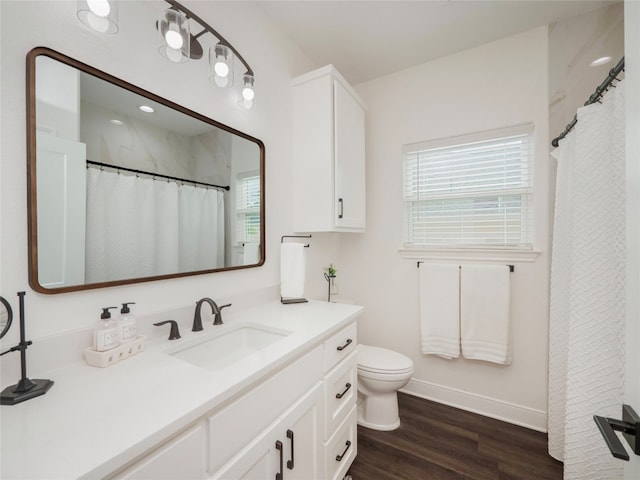 bathroom featuring a healthy amount of sunlight, toilet, hardwood / wood-style floors, and vanity