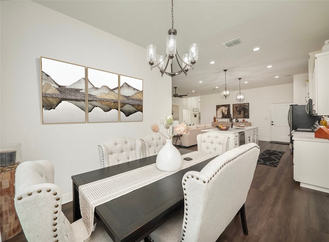 dining space featuring dark wood-type flooring, ceiling fan with notable chandelier, and sink