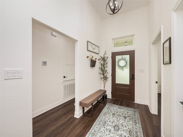 entryway featuring dark wood-type flooring and an inviting chandelier