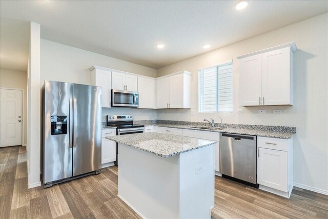 kitchen with white cabinets, a center island, hardwood / wood-style flooring, and stainless steel appliances