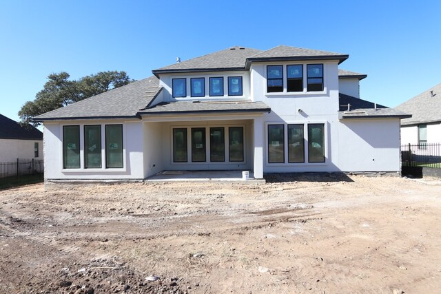 back of property with a patio, a shingled roof, fence, and stucco siding