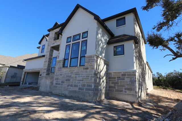 view of front facade with a garage, stone siding, and stucco siding