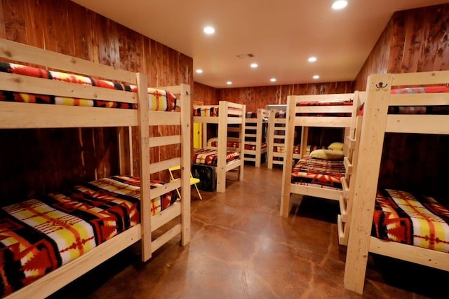 bedroom featuring wooden walls and concrete flooring