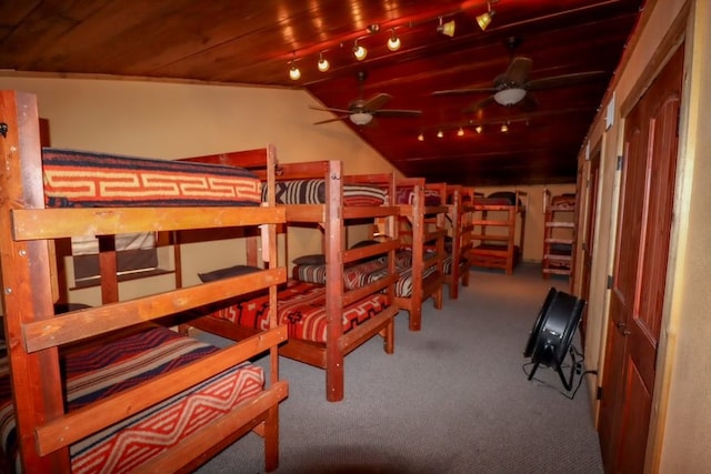 carpeted bedroom featuring lofted ceiling, wooden ceiling, and rail lighting