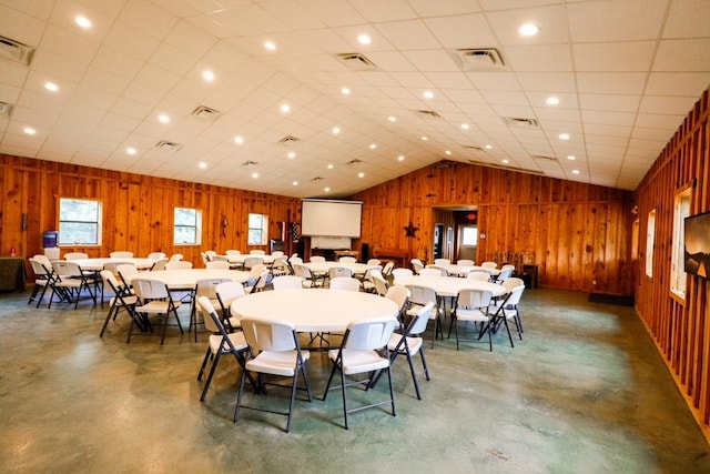 dining room with vaulted ceiling, concrete floors, and wooden walls