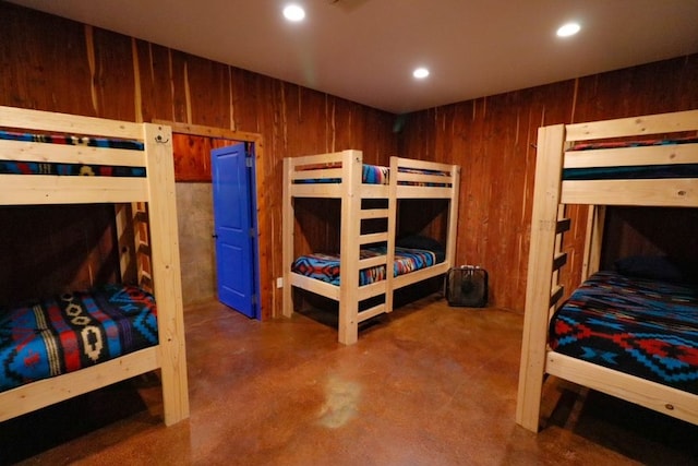 bedroom featuring wooden walls and concrete floors