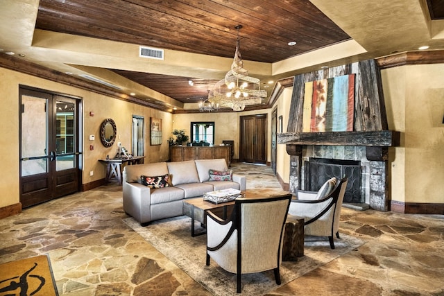 living room with french doors, wood ceiling, a chandelier, a tray ceiling, and a fireplace