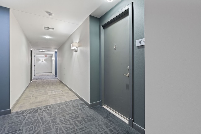 hallway with carpet floors, visible vents, and baseboards