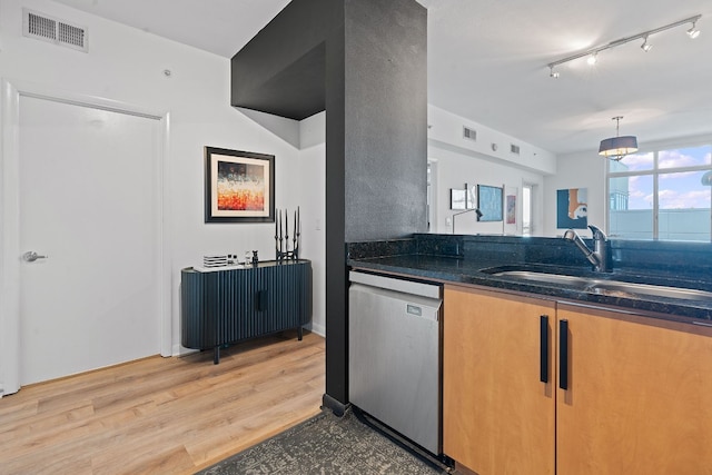 kitchen with sink, stainless steel dishwasher, decorative light fixtures, dark stone counters, and light wood-type flooring