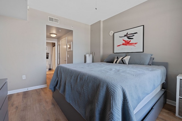 bedroom featuring baseboards, visible vents, and wood finished floors