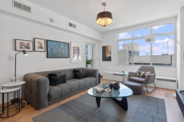 living area with a wealth of natural light, visible vents, and wood finished floors