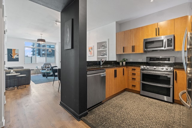 kitchen with pendant lighting, appliances with stainless steel finishes, dark hardwood / wood-style floors, and sink