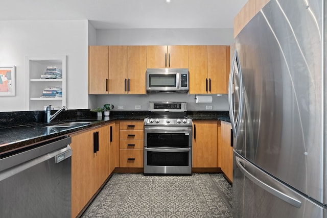 kitchen featuring stainless steel appliances, sink, and dark stone counters