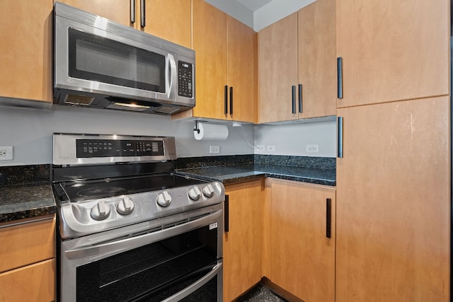 kitchen with dark stone counters and appliances with stainless steel finishes