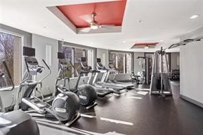 gym with a tray ceiling and ceiling fan