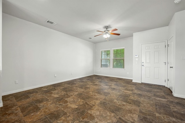 empty room featuring visible vents, baseboards, a ceiling fan, and stone finish floor