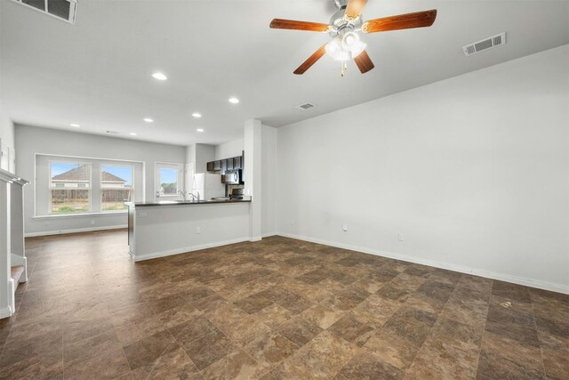 unfurnished living room featuring ceiling fan and sink