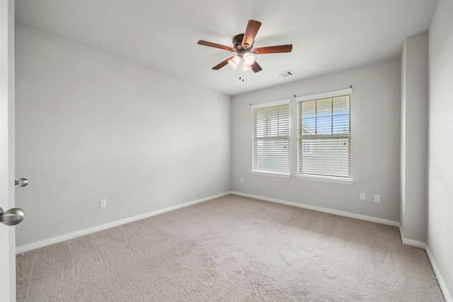 carpeted spare room featuring baseboards, visible vents, and ceiling fan